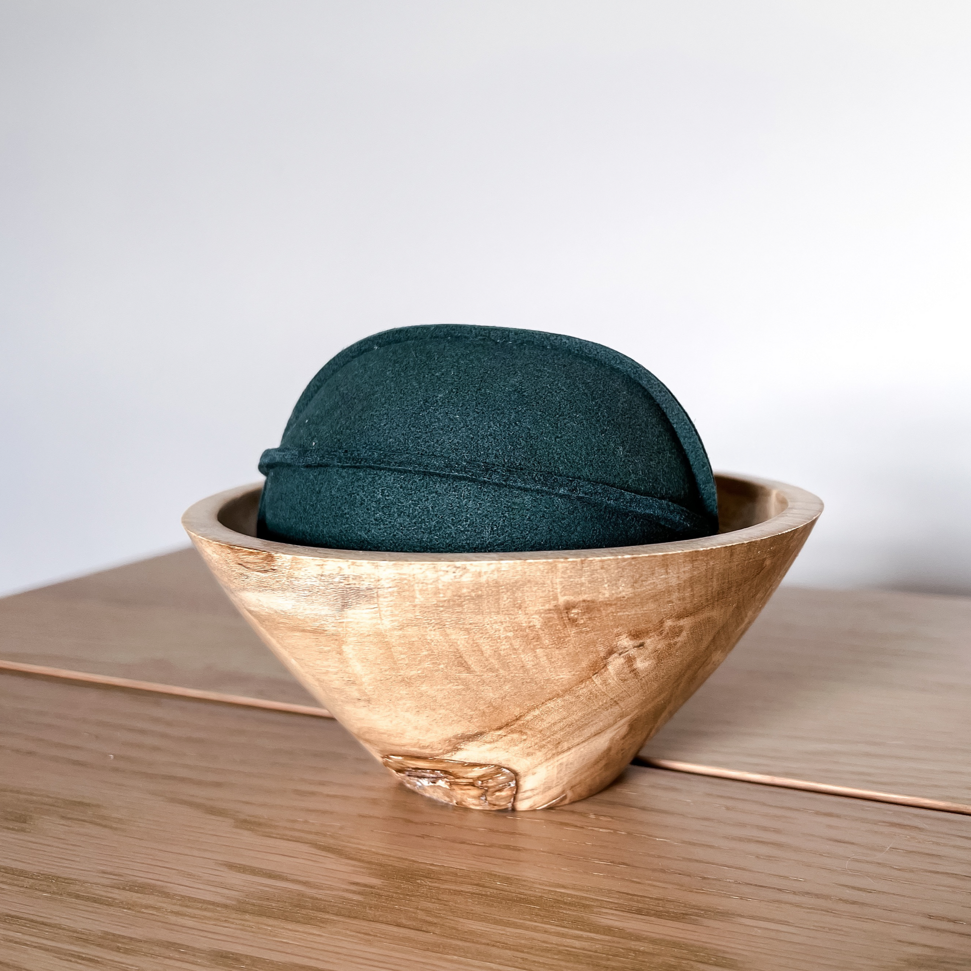 green suede ball dog toy in wooden holder