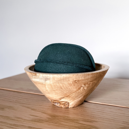 green suede ball dog toy in wooden holder