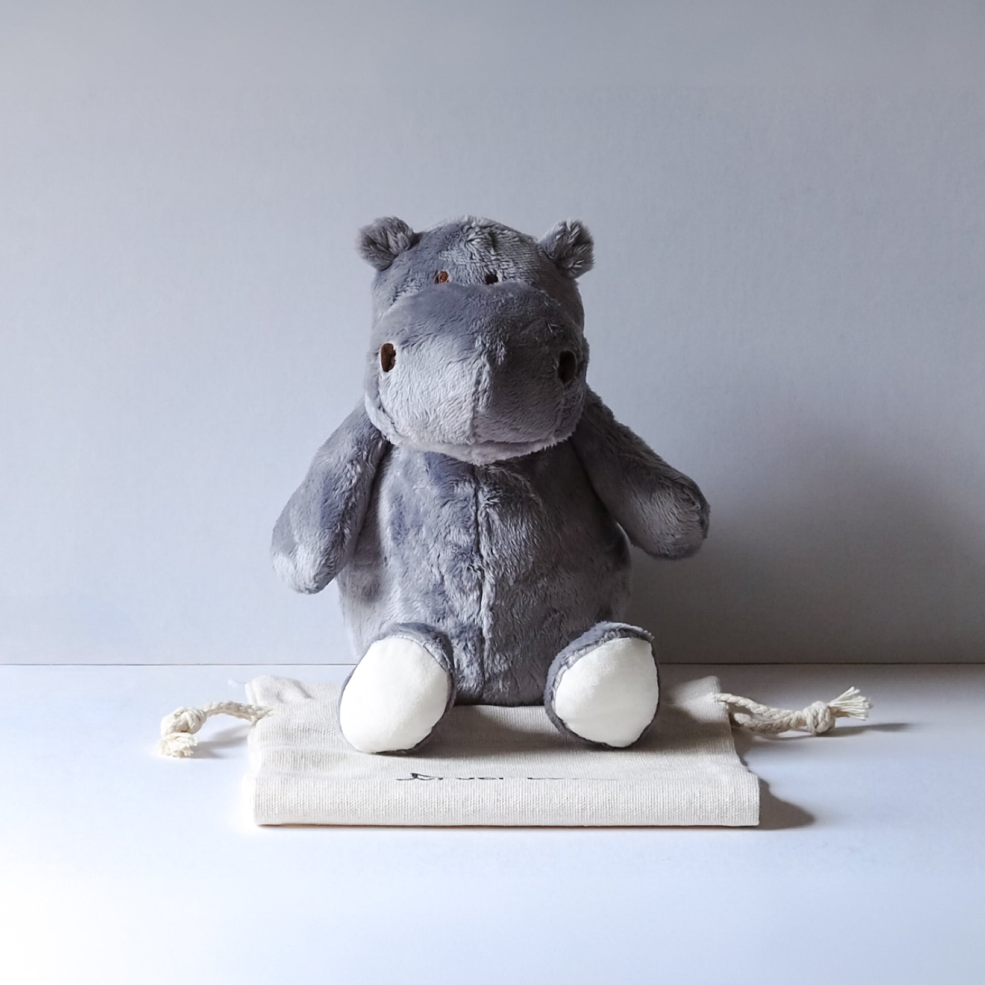 Gray plush hippo toy on a white surface with a light gray background